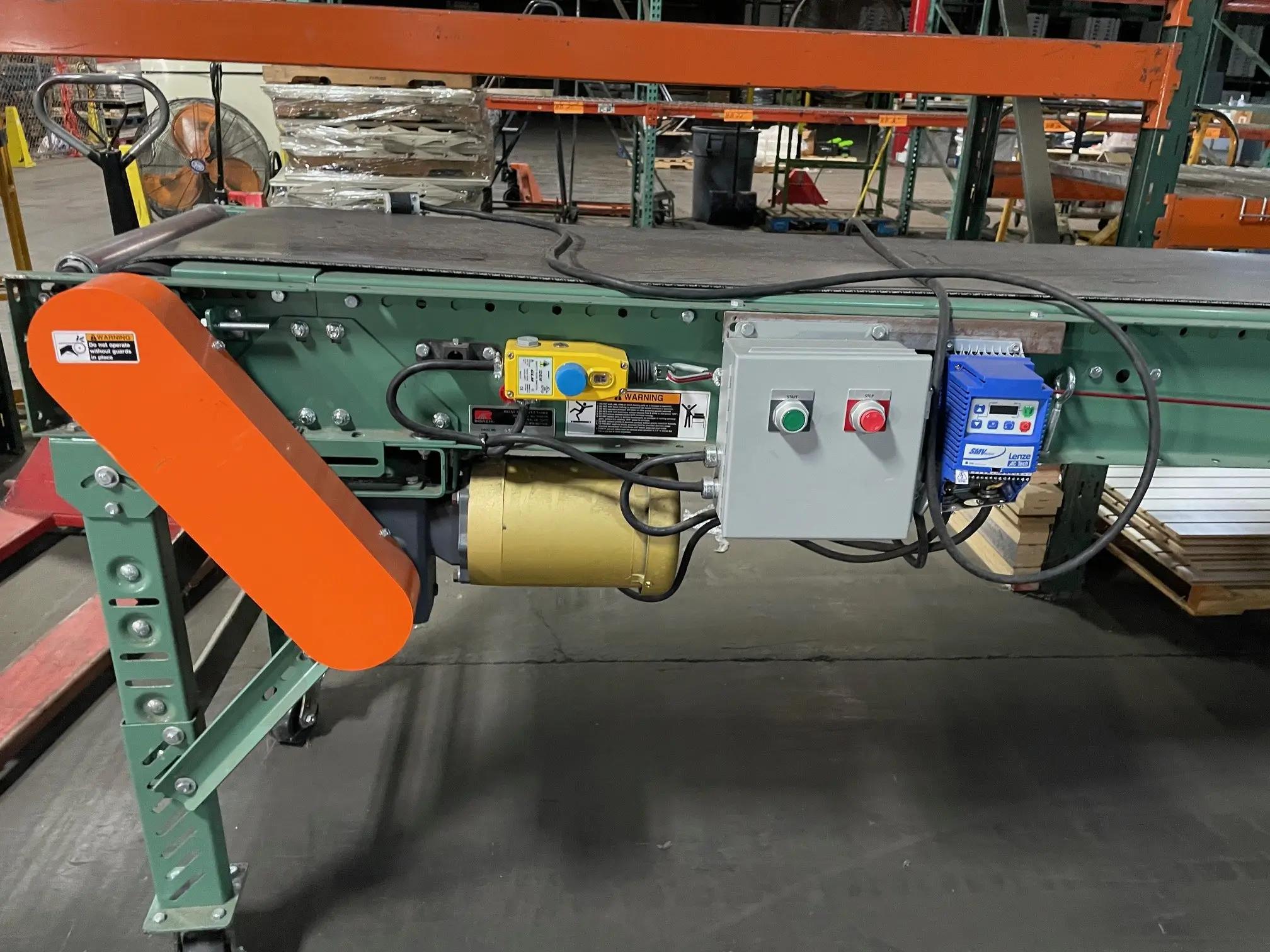 Image of a conveyor belt system in a warehouse setting with visible control panel and safety warnings.