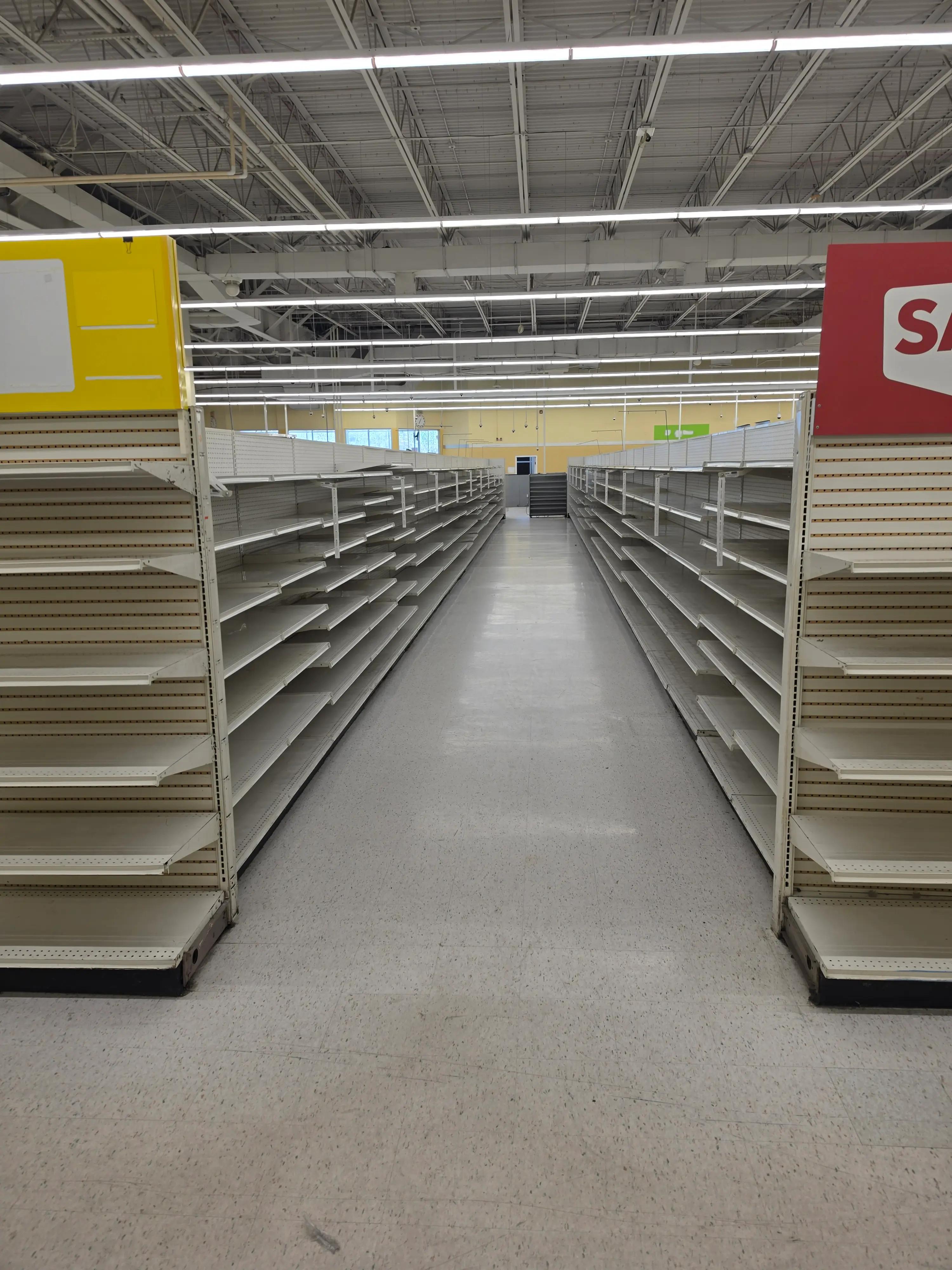 Empty store aisle with metal shelves on both sides, under fluorescent lighting, showcasing a completed renovation or setup by Mid America.