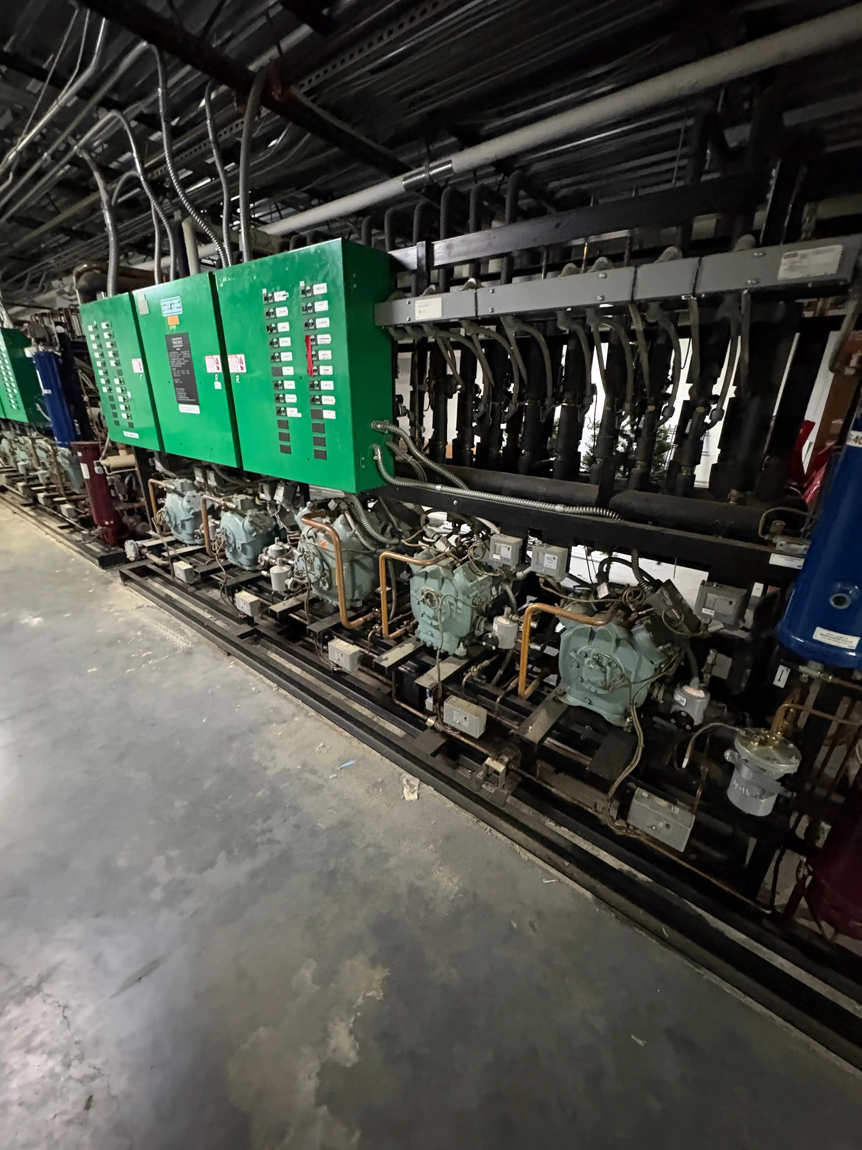 Industrial equipment featuring green control panels, multiple pipes, and valves, part of a project by Mid-America Store Fixtures.