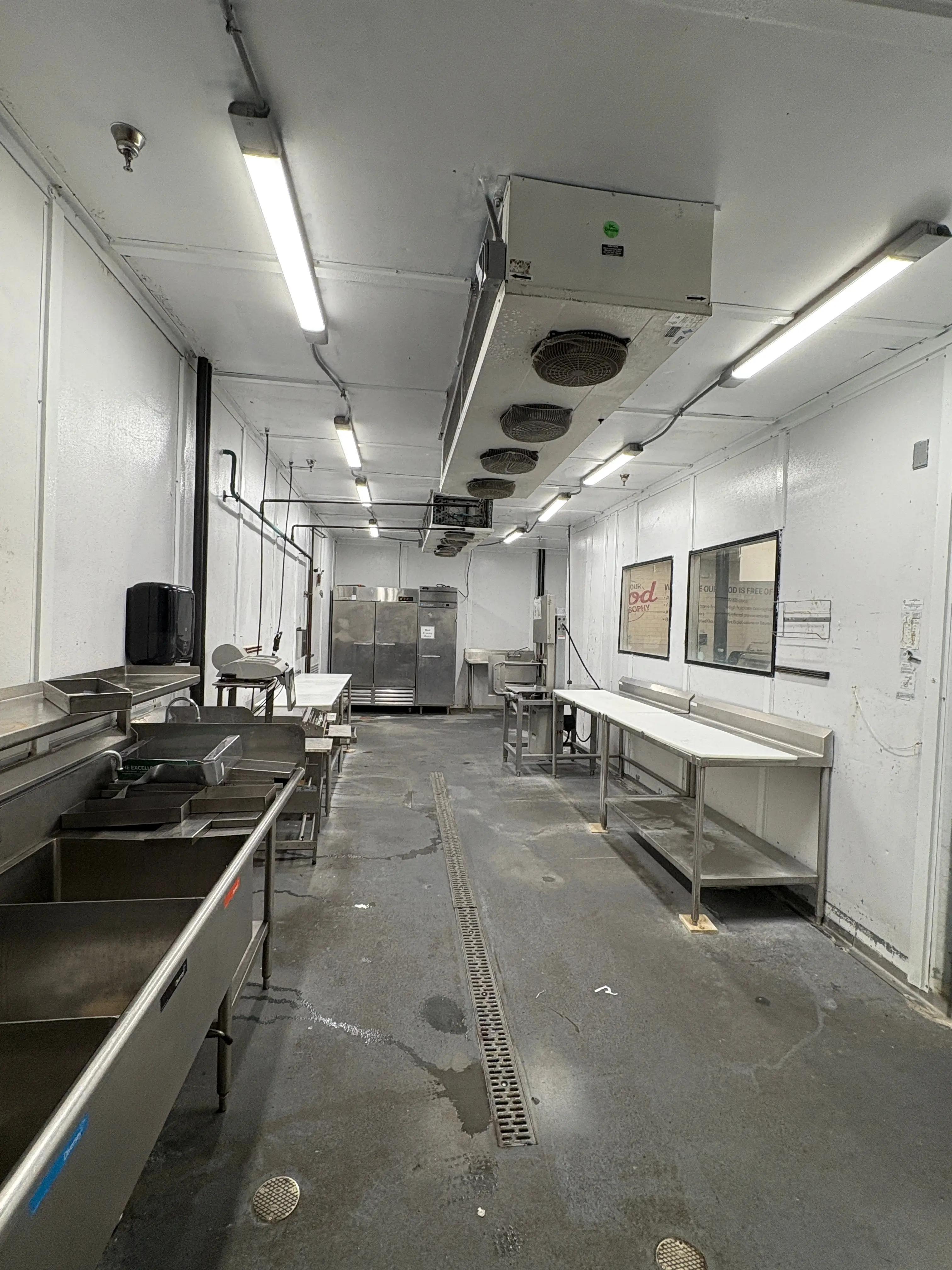 Commercial food preparation room with stainless steel work tables and equipment, used in a food distribution facility and available through Mid-America Store Fixtures