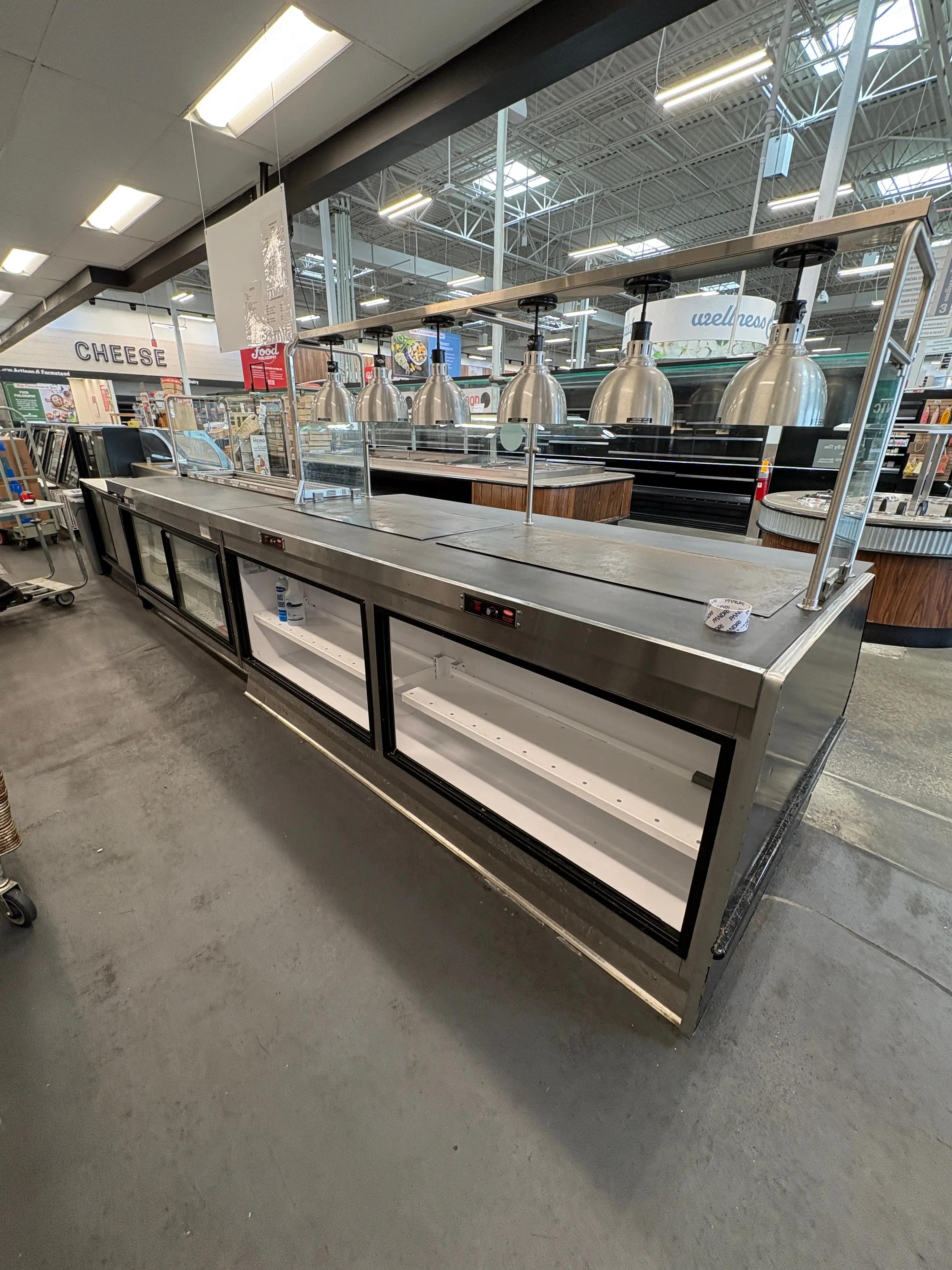 Commercial heated service merchandiser with overhead heat lamps, used for hot food display in grocery and food service operations