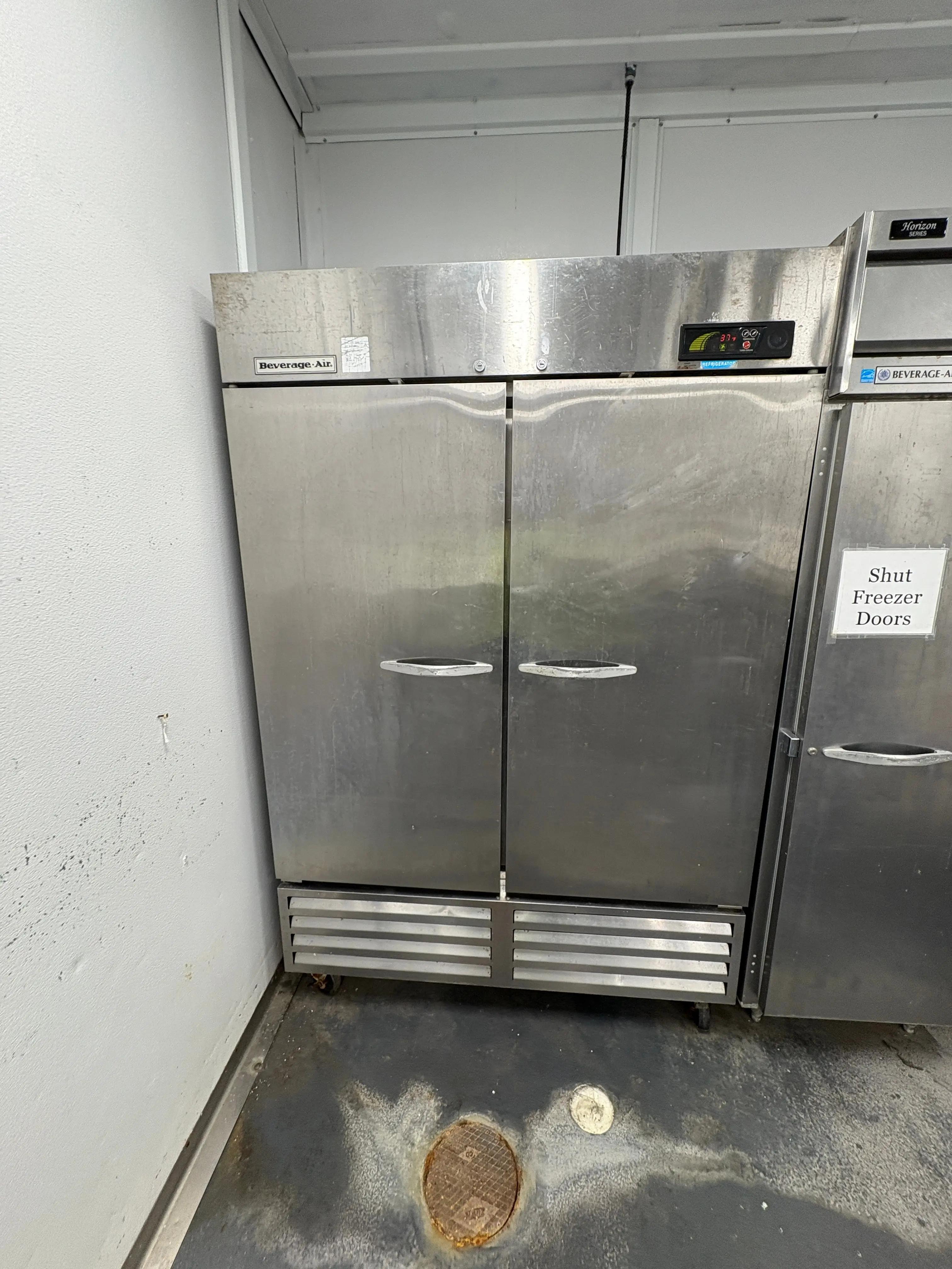 Large stainless steel commercial refrigerator with double doors in a kitchen setting.