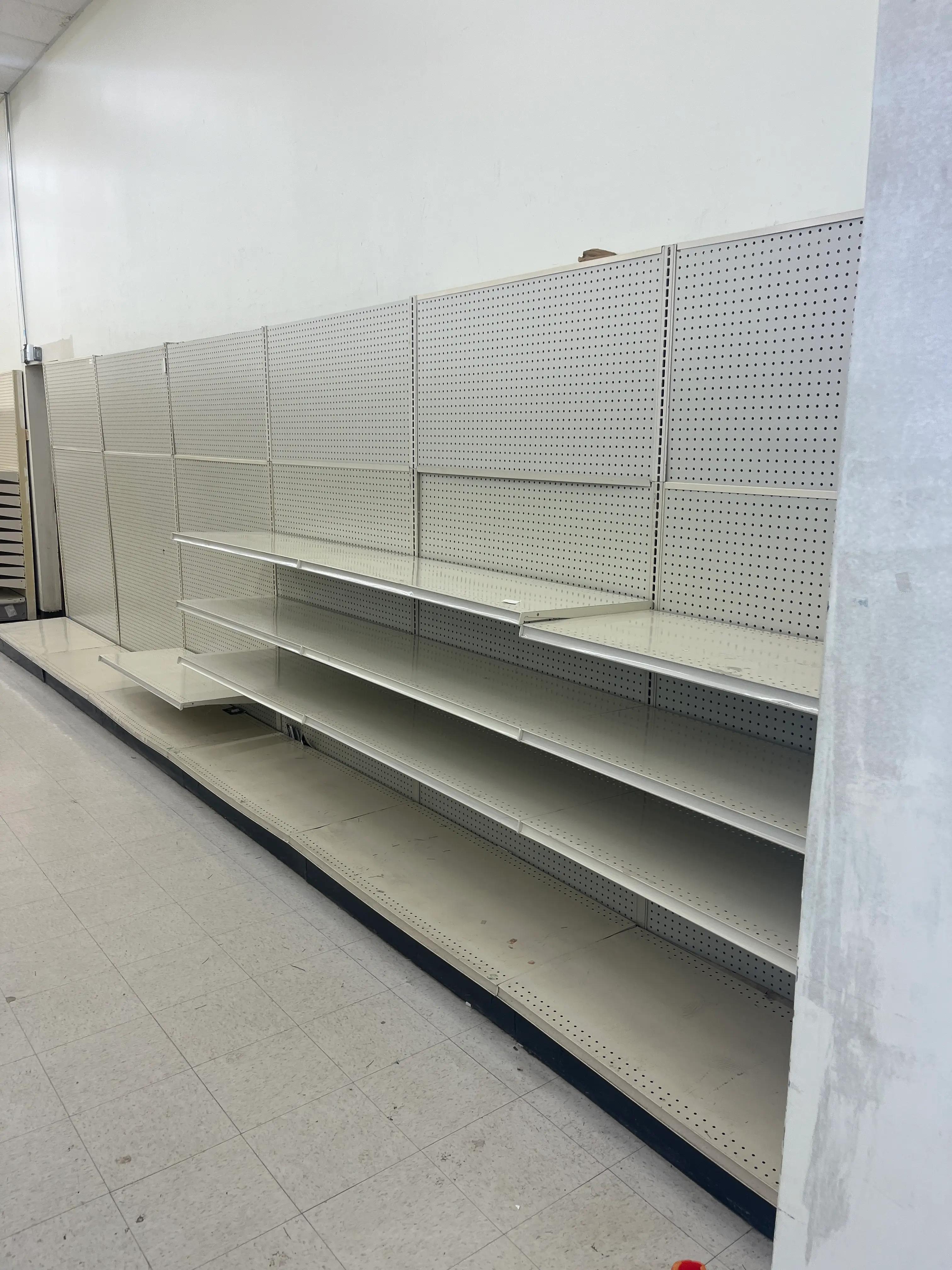 Empty retail shelving units with pegboard backing in a store setting, showcasing a completed installation by Mid America.