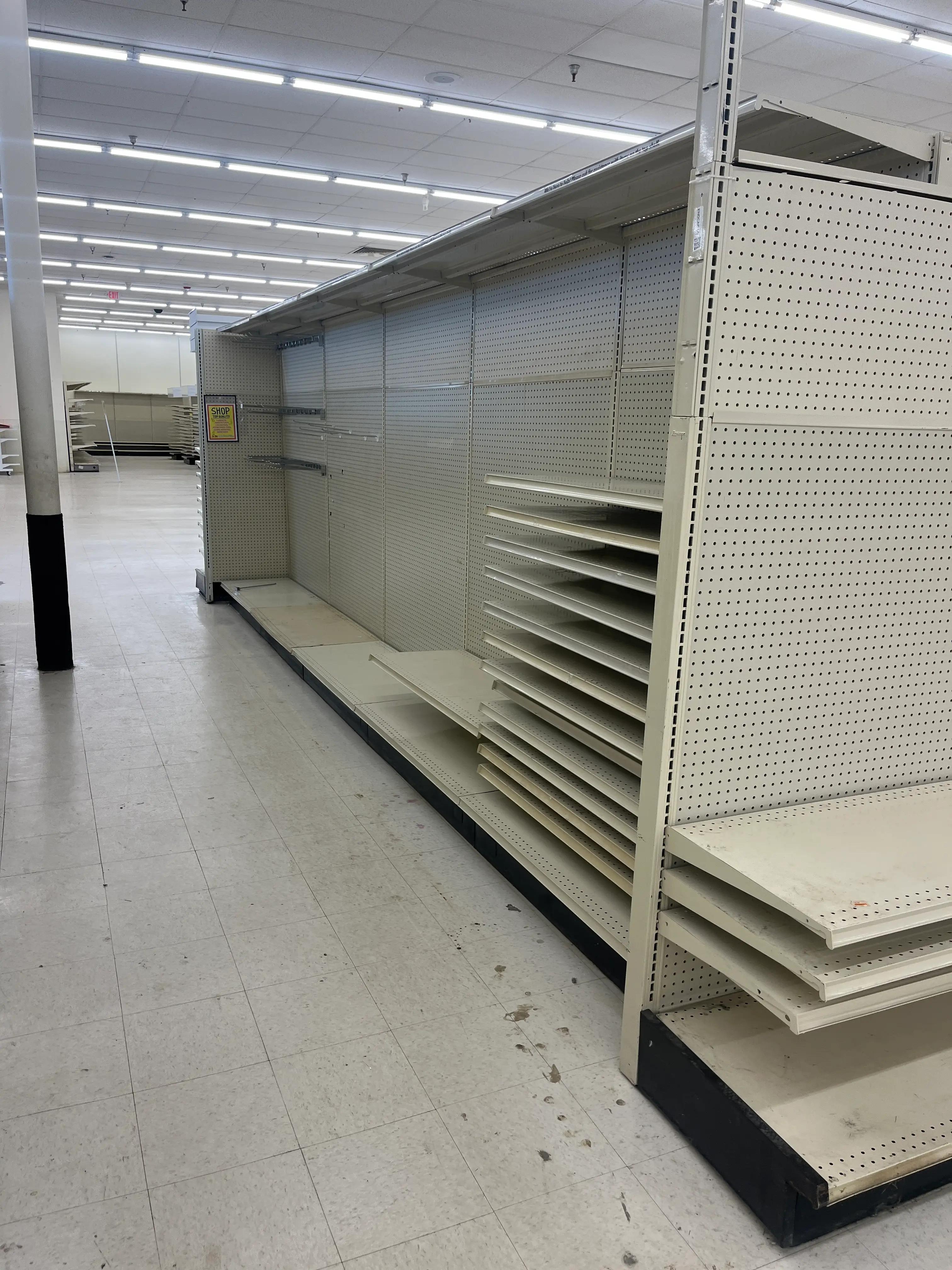 Empty retail store shelves in a large, well-lit space with tiled flooring, showcasing a completed job by Mid America.