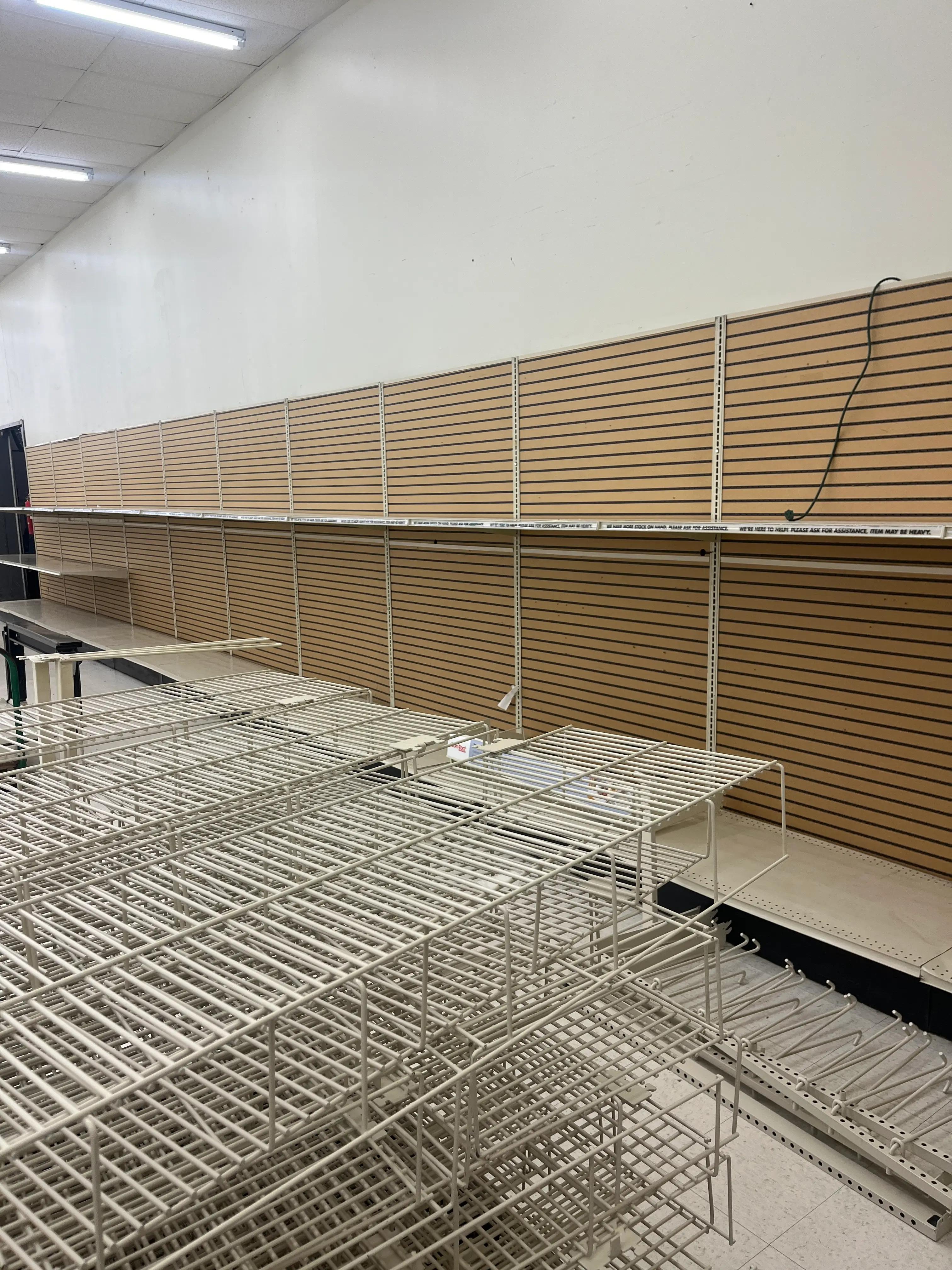Empty retail shelving units with slatwall panels and wire racks, suggesting a restocking or renovation project by Mid America.