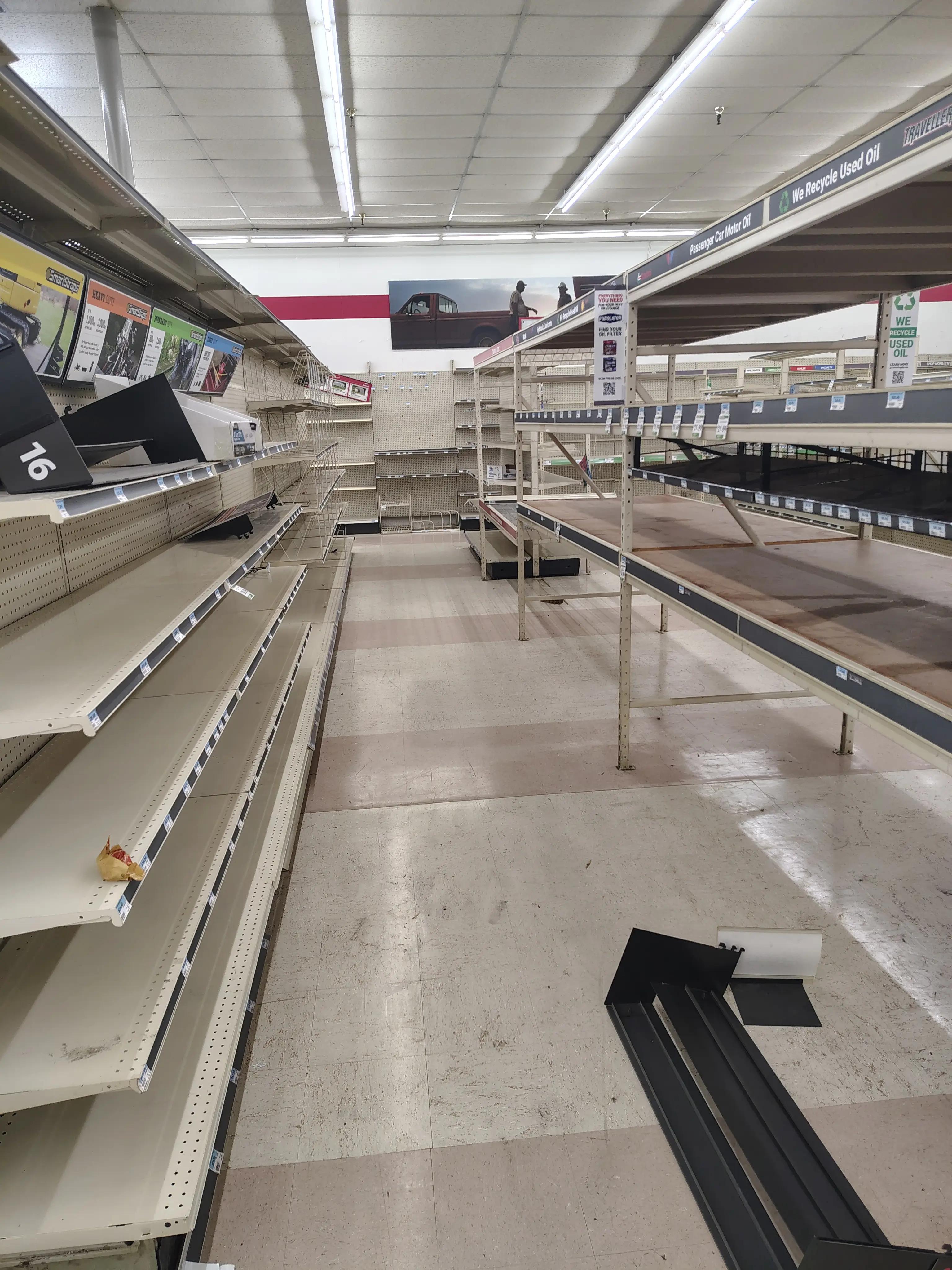 Image of an empty store interior with long aisles and empty shelves, indicating possibly a retail environment or store closure.