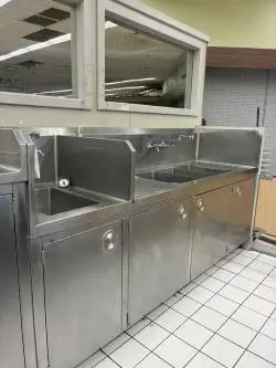 Stainless steel commercial sink station with cabinets for grocery store prep and foodservice operations
