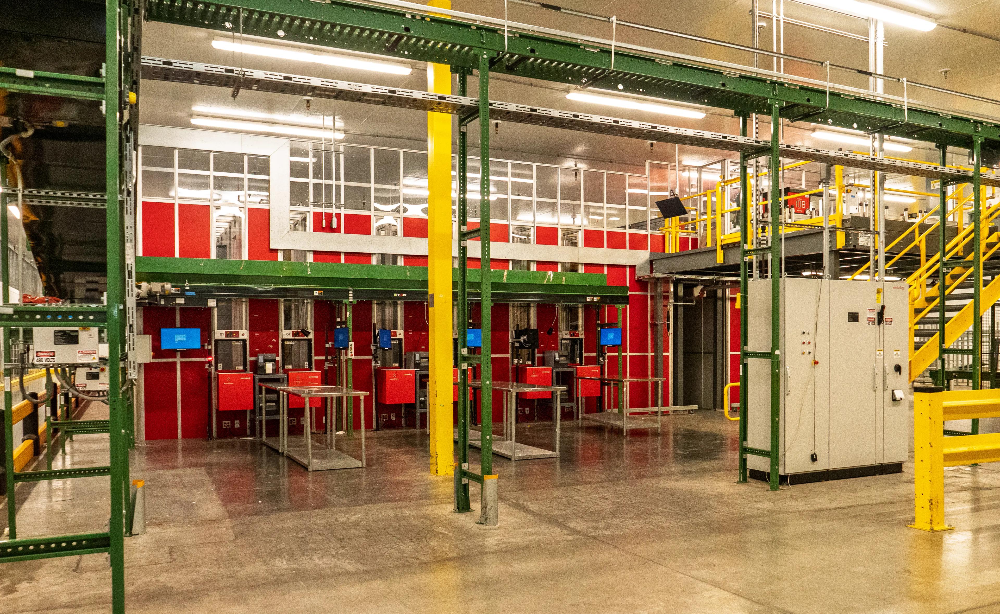 Interior of an industrial facility featuring machinery, conveyor systems, and workstations with bright red and green accents.