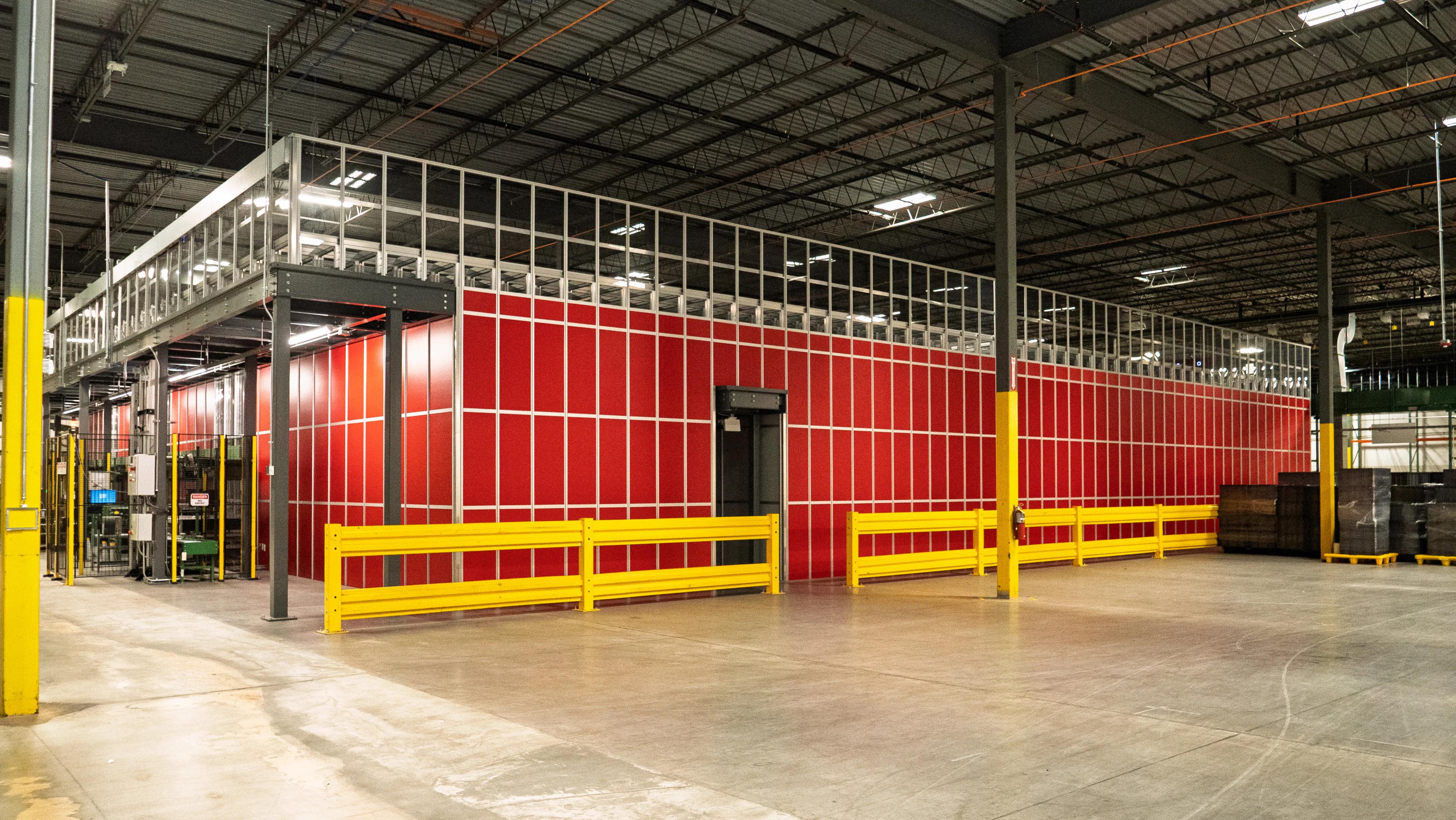 Interior view of a large warehouse with red and yellow partition walls and exposed ceiling beams.