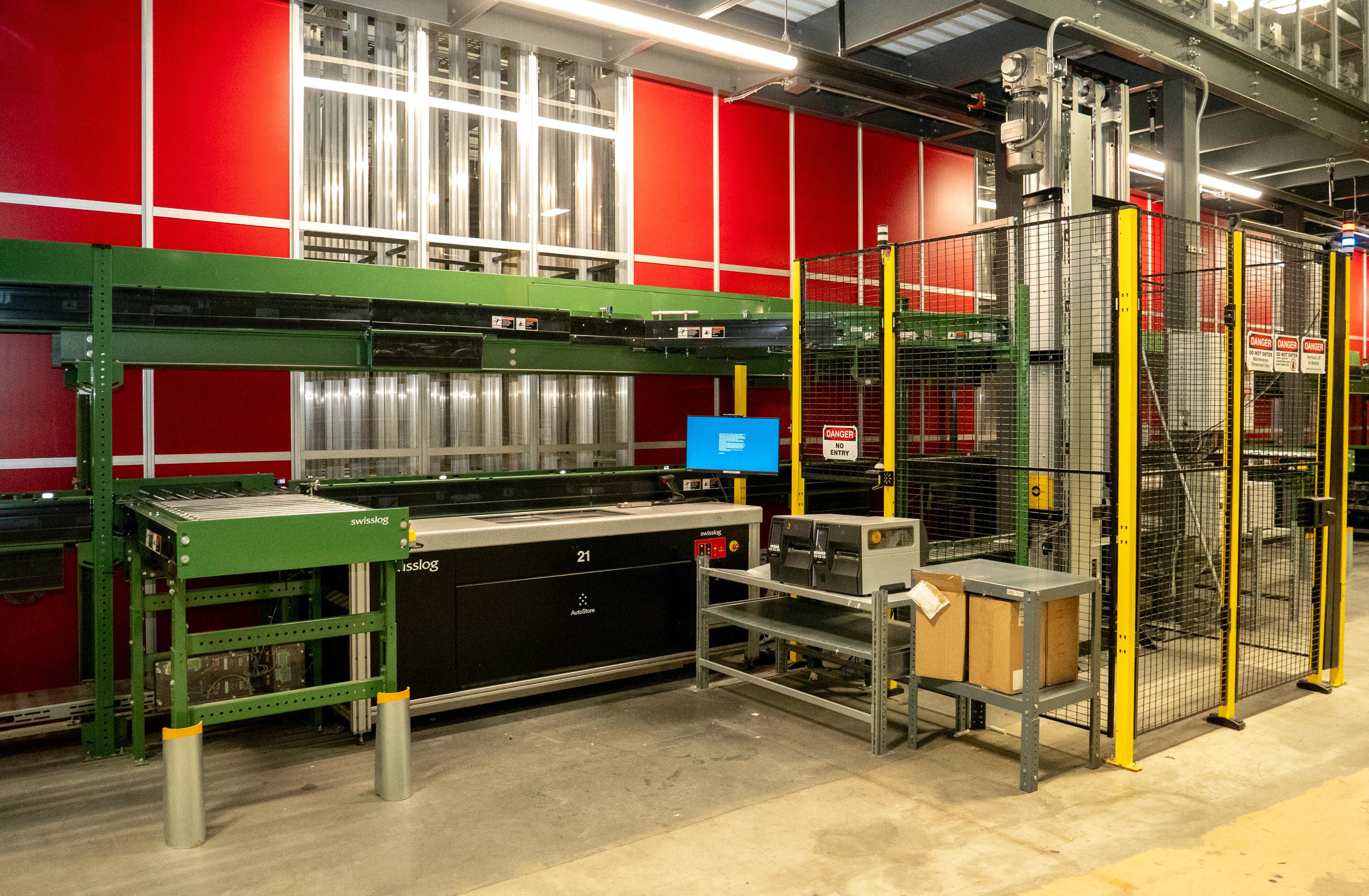 Industrial automation setup with machinery, storage system, and safety barriers in a warehouse environment.