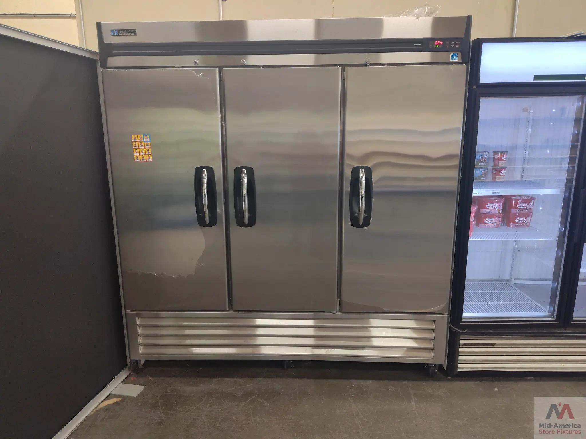 Commercial stainless steel refrigerator with three doors labeled "Master-Bilt" next to a glass-door freezer containing ice cream tubs. The Mid-America Store Fixtures logo is visible in the bottom right corner.