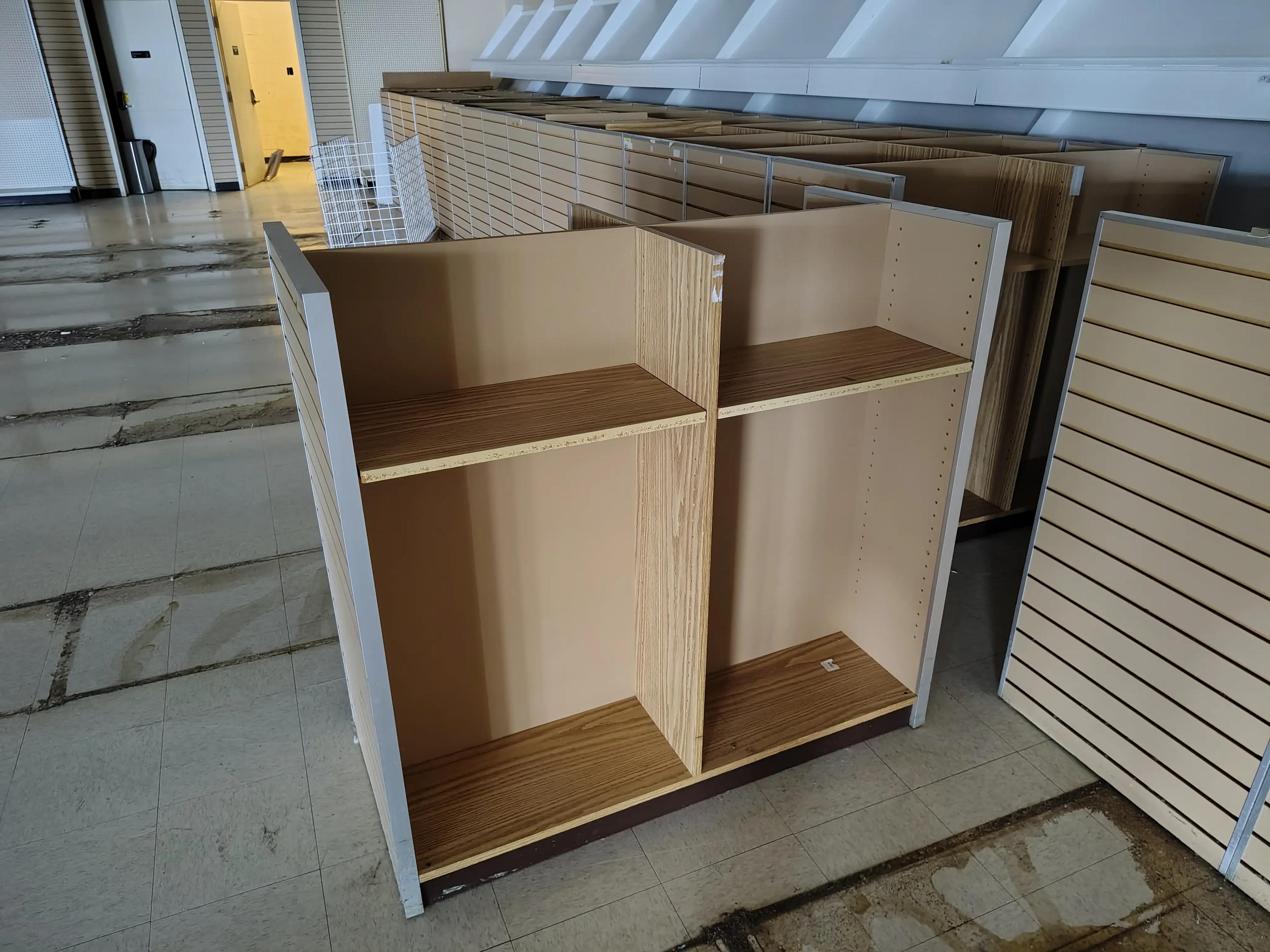 Partially renovated room with wooden shelving units, tiled flooring, and slatwall panels leaning against the wall, showcasing a project by Mid America.