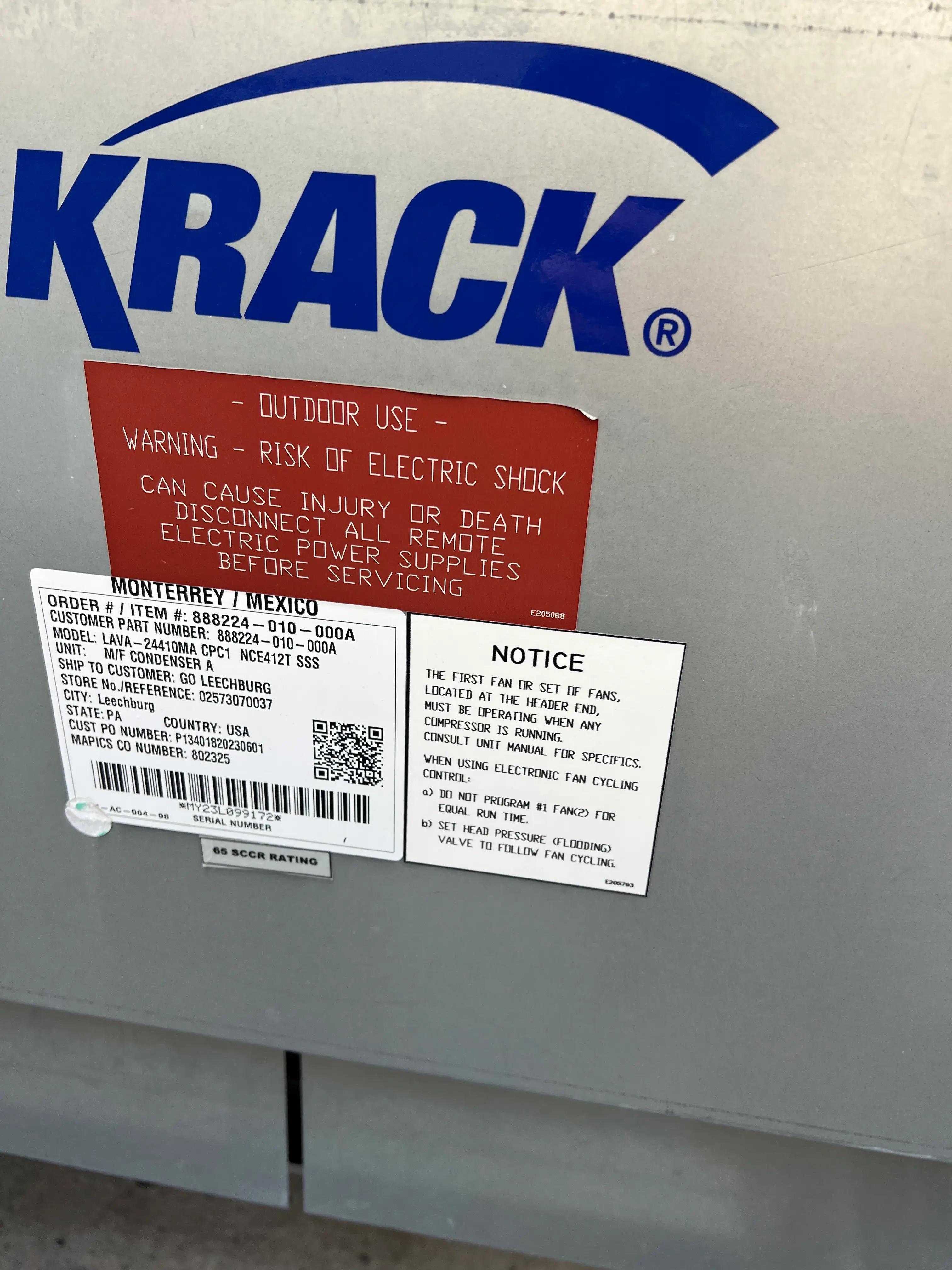 Image of an industrial equipment unit with the brand name 'Krack' and warning labels about risk of electric shock. Includes a white notice sign with operational instructions and specifications.