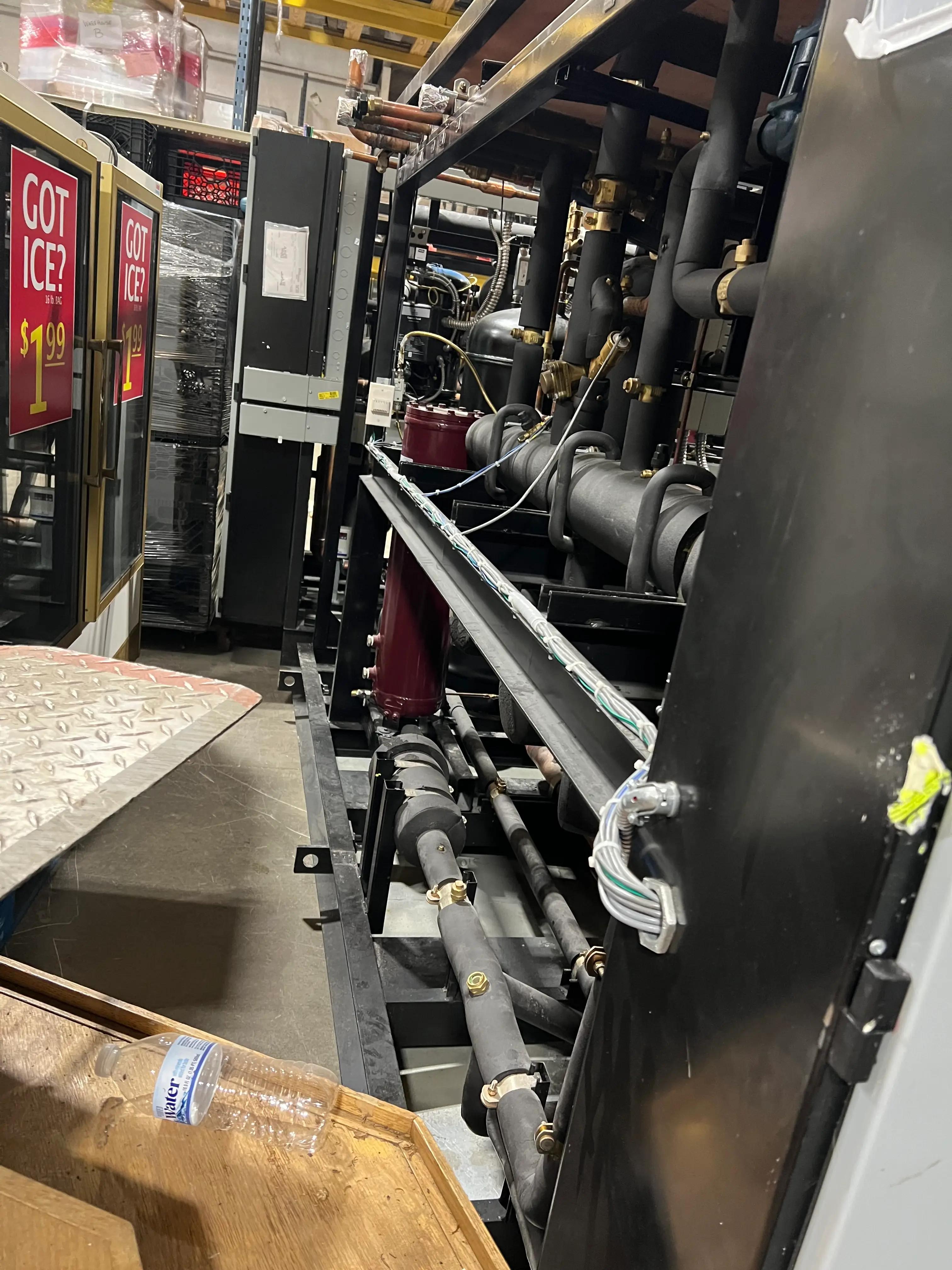 Industrial machinery with pipes and refrigeration units in a warehouse setting.