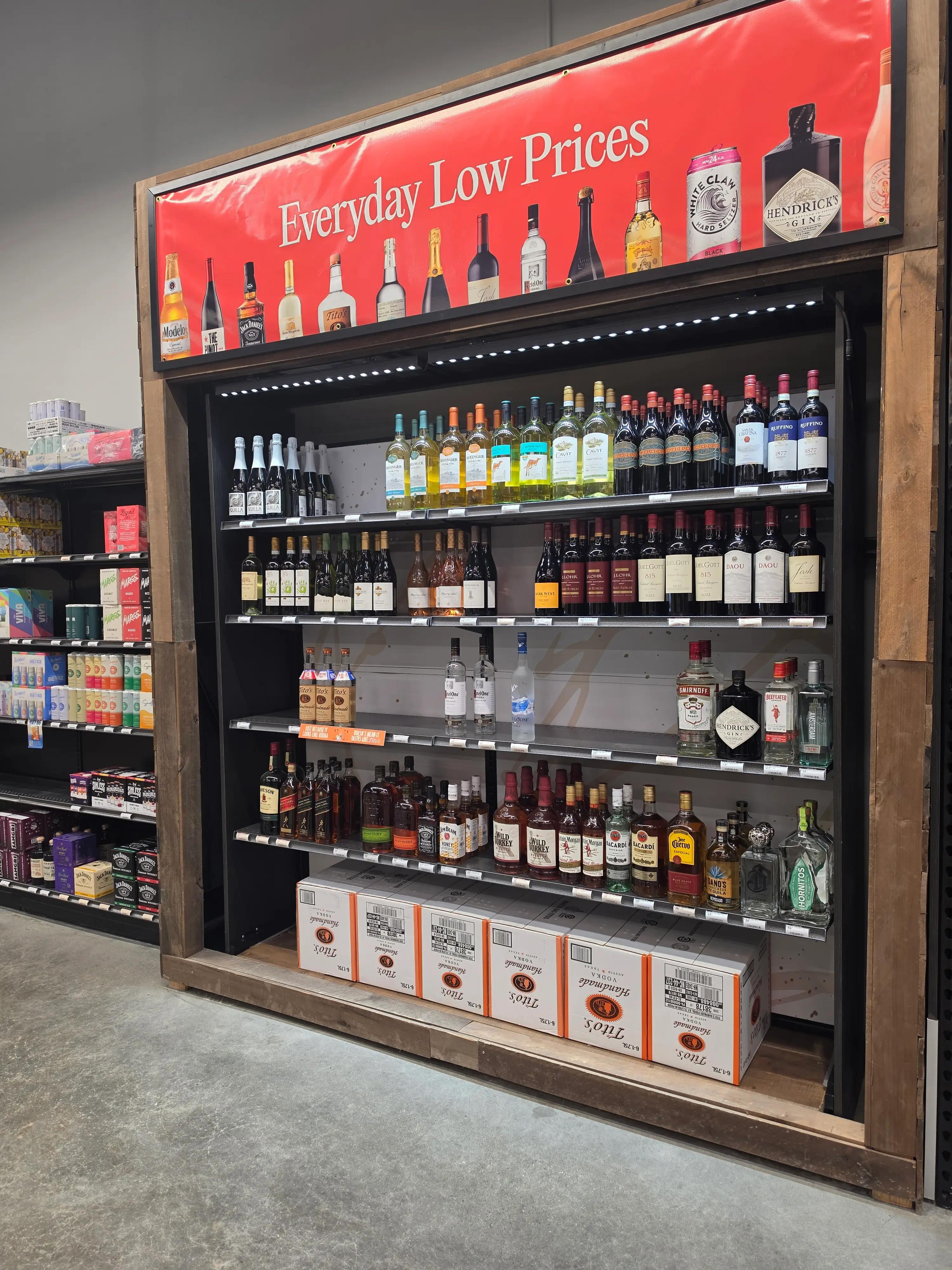 Shelves displaying various alcoholic beverages under a sign that reads "Everyday Low Prices," featuring brands such as Hendrick's Gin, Tito's Vodka, and Modelo.