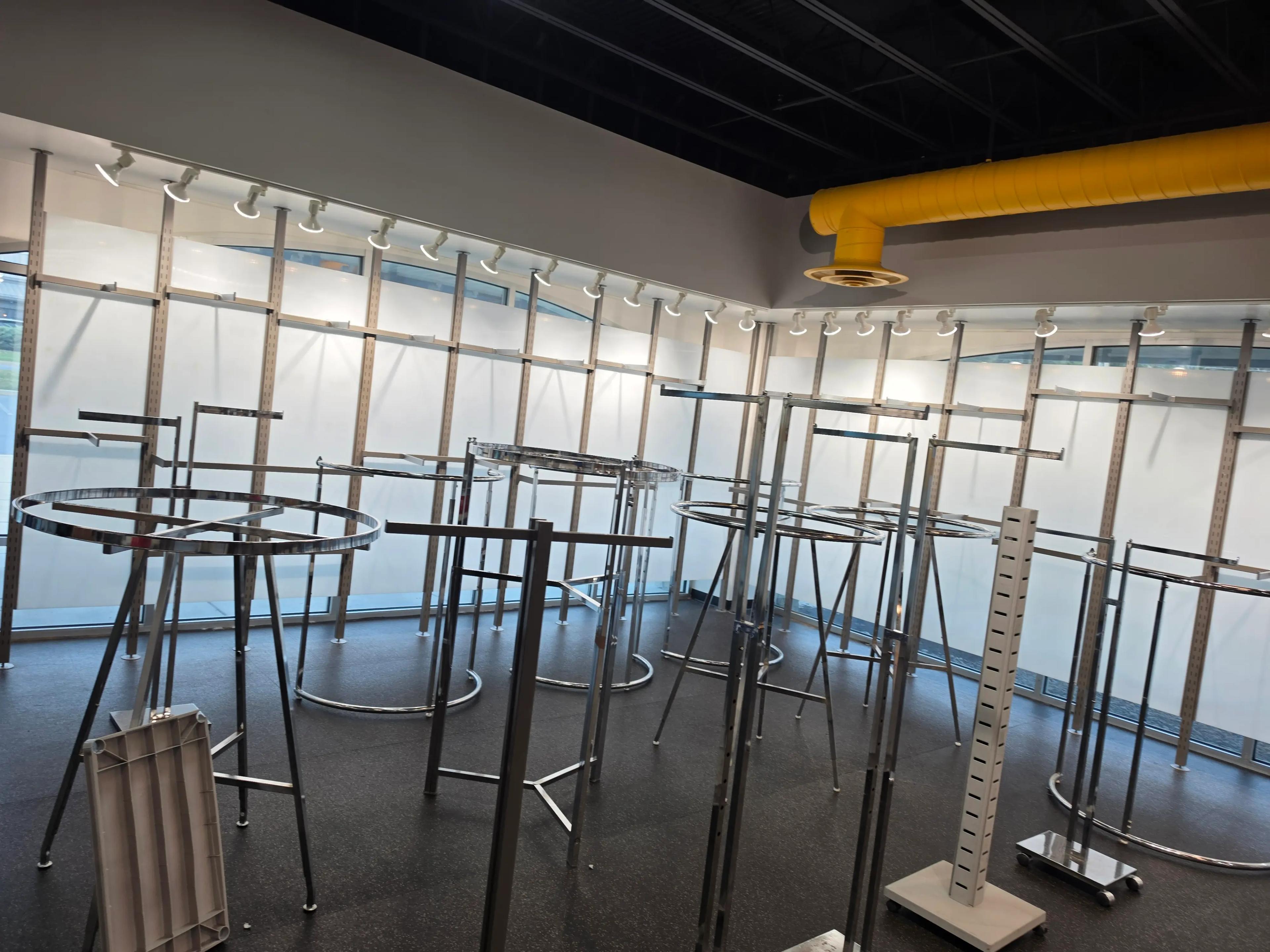 Interior view of a retail space featuring metal clothing racks and a prominent yellow ventilation duct on the ceiling, representing a project by Mid America.