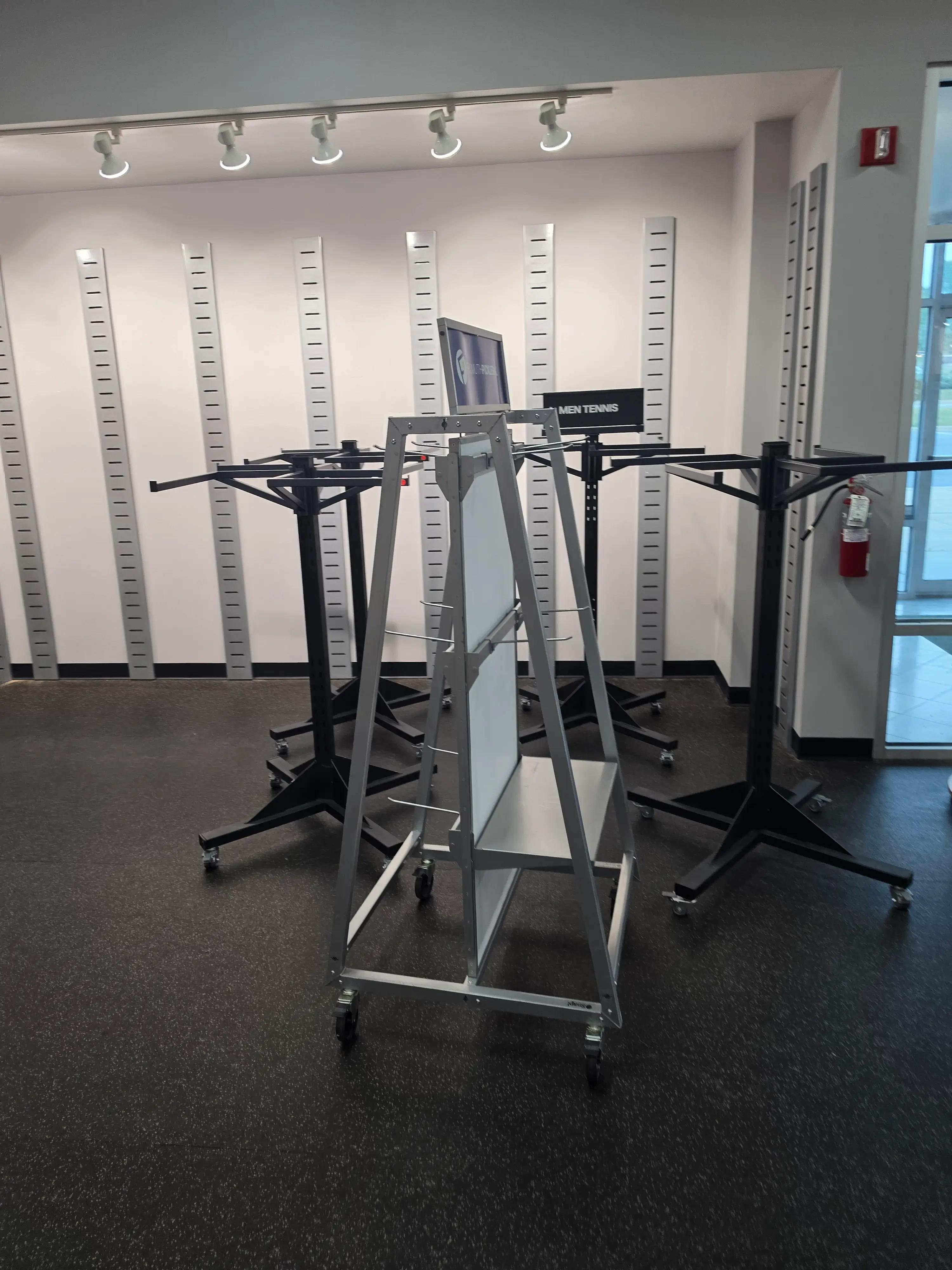 Showroom display racks and stands featuring tennis equipment with a "MEN TENNIS" sign in the background, highlighting Mid America's work.