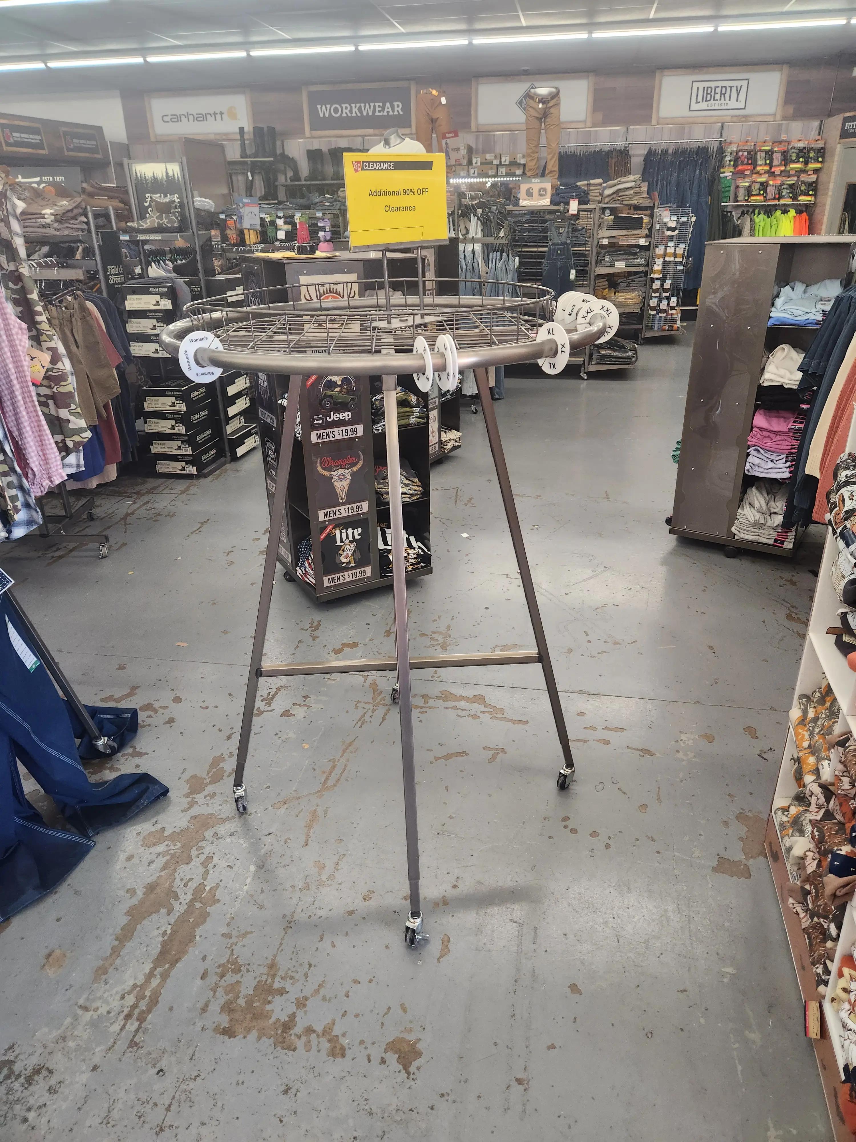 Retail store interior with clothing racks displaying various apparel. A yellow sign indicates an additional 30% off clearance. Brands like Carhartt and Liberty are visible, showcasing workwear and casual clothing.