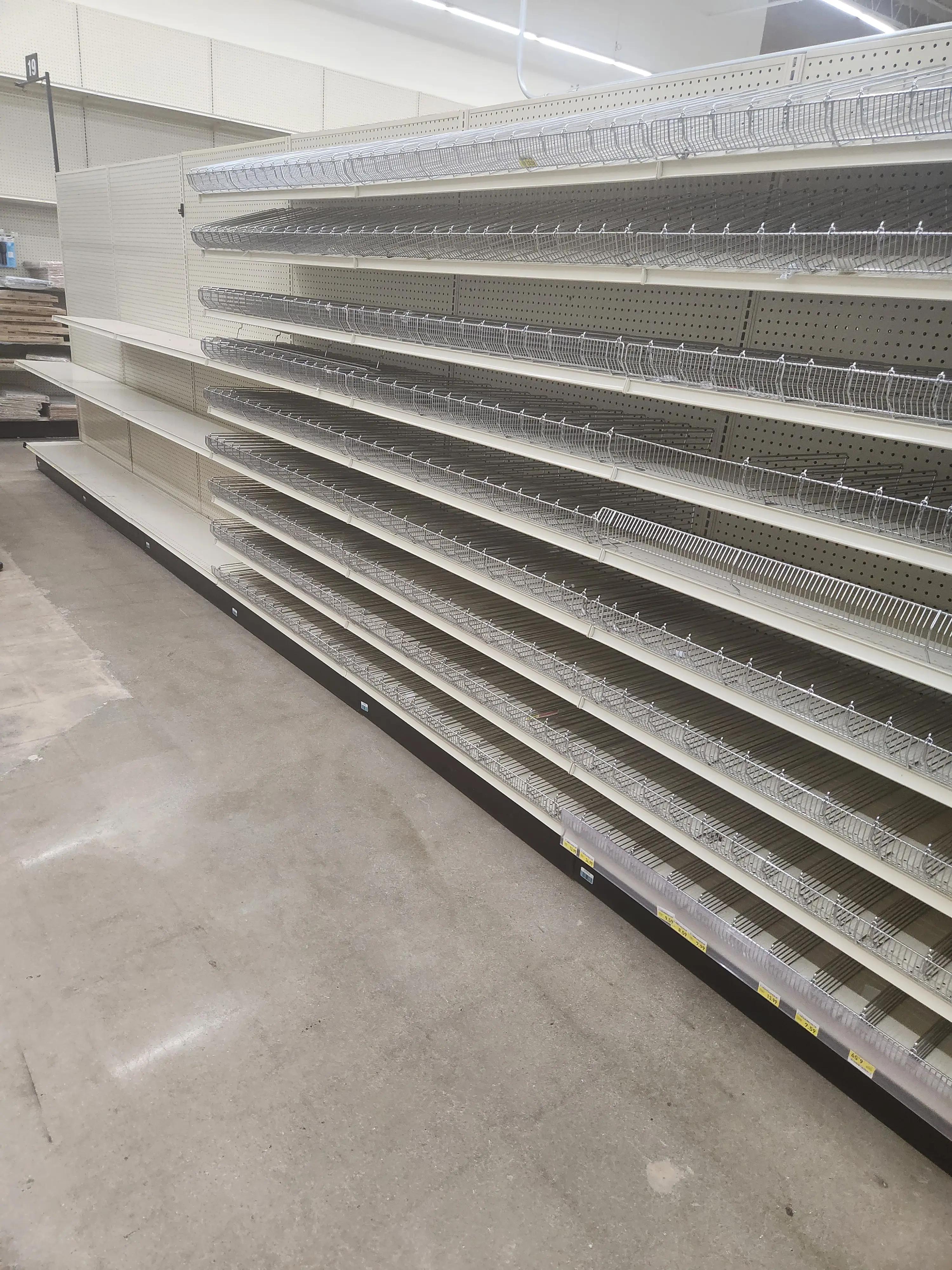 Image of empty shelving units in a retail store with clean floors and ceiling lights.